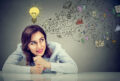 Thinking happy business woman sitting at desk planning